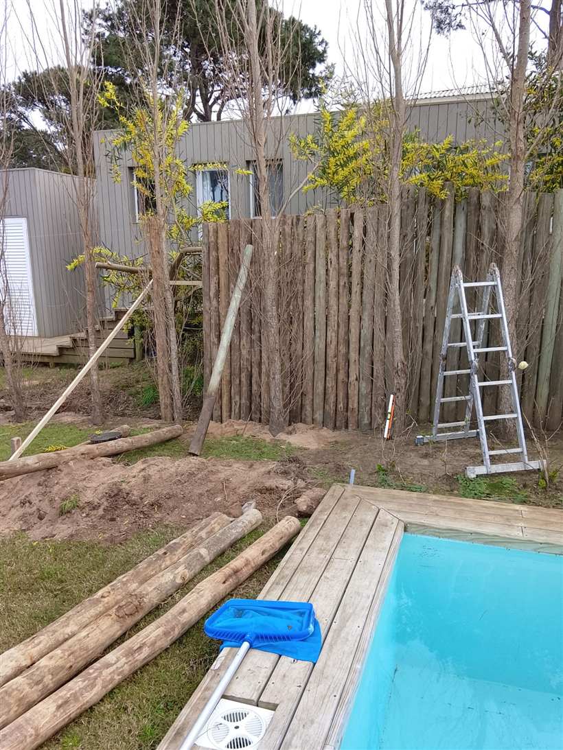 Cerco de troncos en construcción junto a la pileta, con escalera y materiales