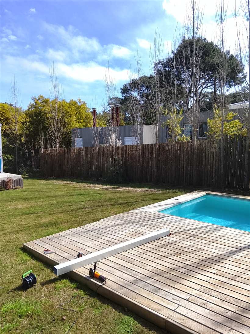 Cerco de troncos terminado a lo largo del jardín, junto al deck de la pileta